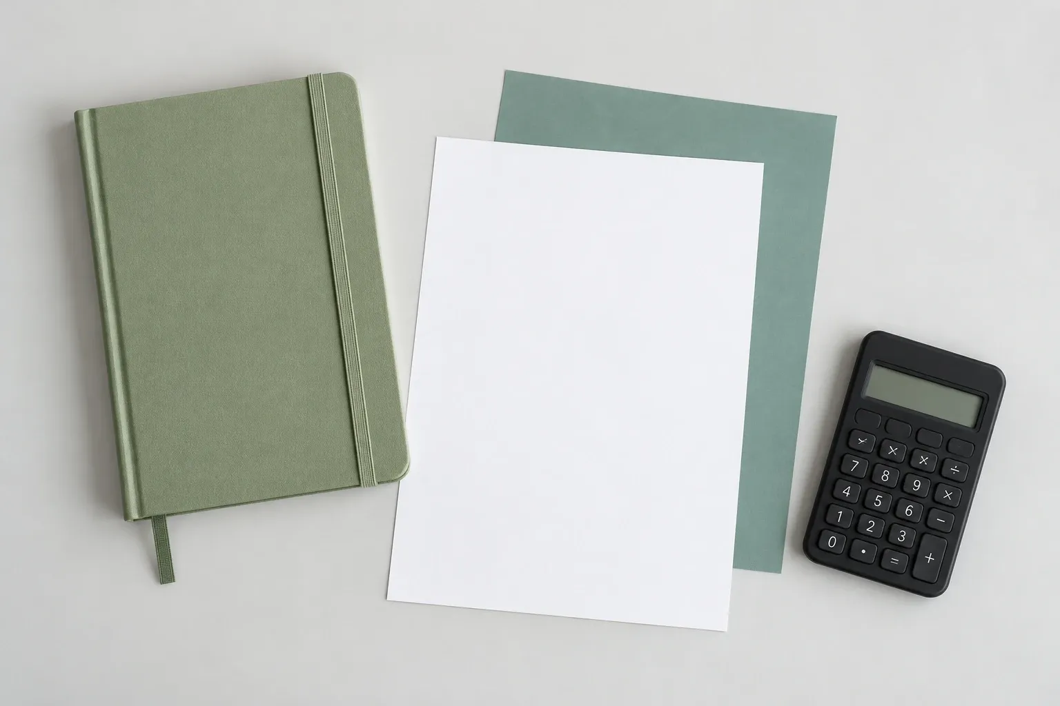 Groene notitieboek, blanco papieren en zwarte rekenmachine op lichtgrijze ondergrond